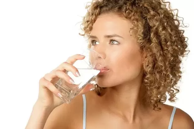 Dívka dodržuje dietu pro lenochy, před jídlem vypije sklenici vody